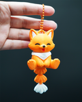Cute orange 3D-printed fox keychain by WiggleNest, featuring a smiling face, white chest, articulated fluffy tail, and orange ball-chain attachment.
