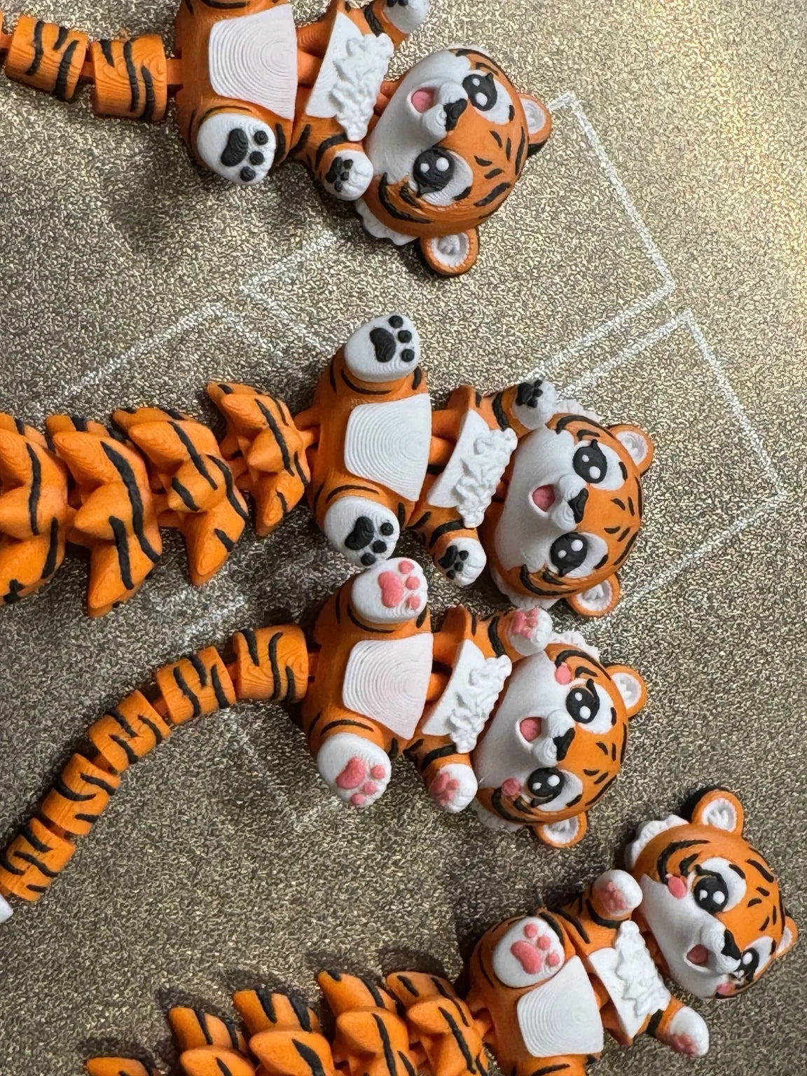 Collection of cute articulated 3D printed tiger toys with flexible tails, perfect as gifts, desk companions, and fidget toys from WiggleNest.